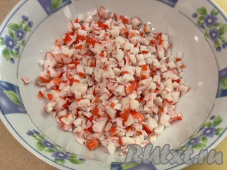 Пока кабачковые блины остывают, приготовим начинку для закусочного торта. Для этого крабовые палочки нужно очистить от слюды, мелко нарезать, сложить в глубокую миску.