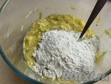 Всыпать примерно половину муки в миску с кабачково-яичной массой, перемешать ложкой&nbsp;до однородности.