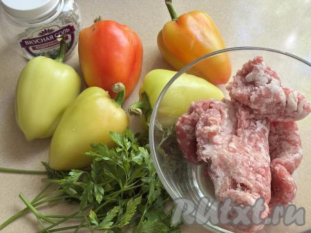 Подготовить продукты для приготовления перца, фаршированного половинками, на сковороде. Болгарский перец лучше брать мясистый. Зелень (у меня - петрушка, можно взять и укроп, зелёный лук) промыть водой. Для этого блюда можно приготовить фарш из любого мяса (у меня - свинина), пропустив его вместе с очищенной луковицей через мясорубку в миску. Можно взять и любой покупной фарш, но тогда к нему нужно будет добавить пропущенный через мясорубку (или прокрученный в измельчителе, или натёртый на тёрке) лук.