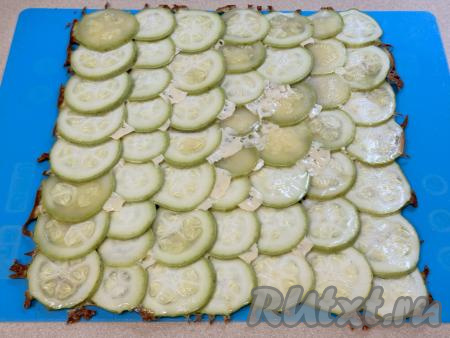 Готовый корж из кабачков, запечённых под сыром, перевернуть на силиконовый коврик (или на новый лист пергамента), чтобы кабачки оказались сверху. Дать немного остыть.