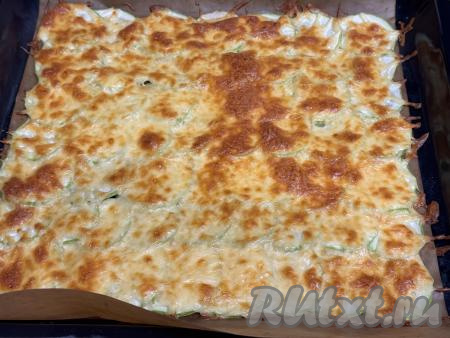 Поместить противень в разогретую до 180 градусов духовку и выпекать кабачковый корж минут 20. Сыр должен расплавиться и стать золотистым.