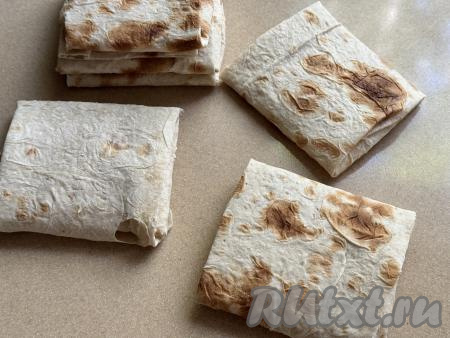 Начиная со стороны с начинкой из колбасы и сыра, сделать несколько оборотов лаваша. Получится прямоугольный конвертик из лаваша с начинкой внутри. Аналогично сформировать все 6 конвертиков.