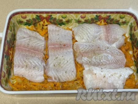 Филе пангасиуса нарезать на порционные кусочки, посолить (я использовала соль, смешанную с сушёной зеленью), поперчить, выложить в форму для запекания поверх моркови и лука в один слой.&nbsp;