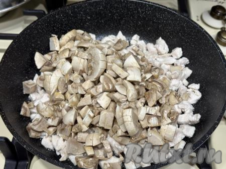 Затем к мясу добавить мелко нарезанные шампиньоны, перемешать курицу с грибами.