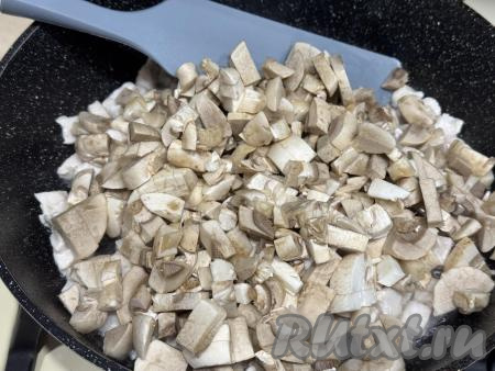 Шампиньоны мелко нарезать, добавить в сковороду с обжаренным куриным мясом, перемешать.