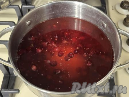В кастрюлю с размятой клюквой влить 500 миллилитров холодной воды, всыпать сахар, перемешать, поставить на сильный огонь.