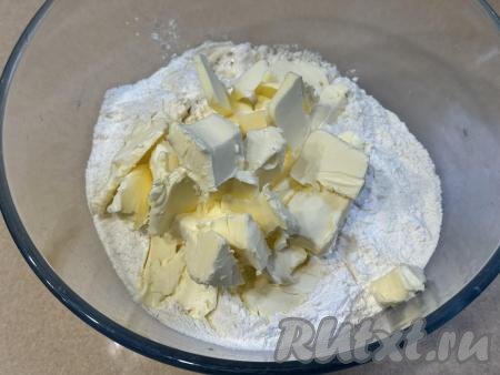 Сливочное масло достать из холодильника, нарезать на небольшие кусочки в миску с получившейся мучной смесью, сразу перетереть массу руками до получения мелкой песочной крошки.&nbsp;