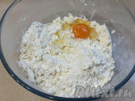 В миску с песочной крошкой вбить сырое яйцо, начать перемешивать столовой ложкой, замешивая тесто. 