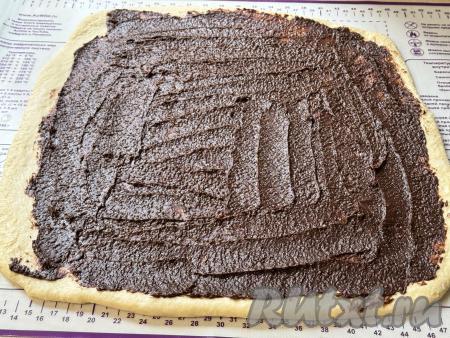 Смазать раскатанное тесто шоколадным кремом, отступив от краёв теста 1-2 сантиметра.