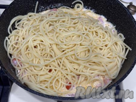Добавить спагетти в сковороду с беконом, помидорами, сливками и сыром, перемешать получившуюся карбонару.