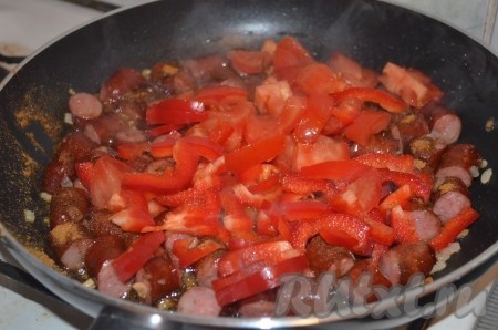 Помидоры очистить от шкурки, нарезать кубиками. Сладкий перец нарезать соломкой. Добавить перец и помидоры в сковороду и потомить 5 минут.
