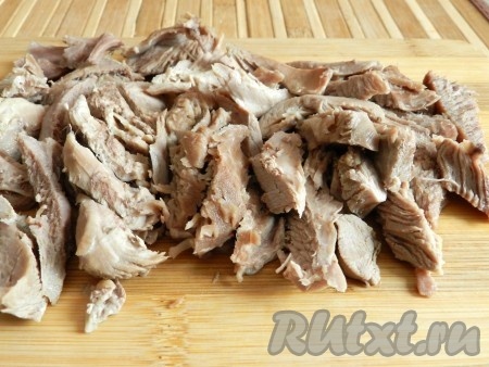 Сварившееся мясо вынуть из бульона,  нарезать небольшими кусочками.