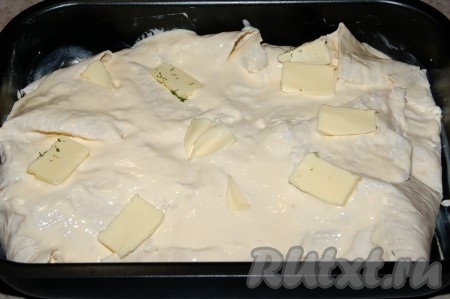 Поверх заливки разложить маленькие кусочки сливочного масла по всей поверхности пирога.