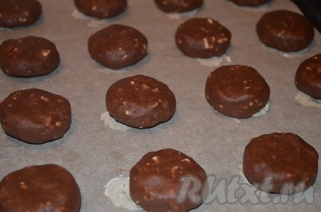 Из шоколадного теста сформировать печенье в виде шариков, слегка их приплюснуть и выложить на противень, застеленный бумагой для выпечки.