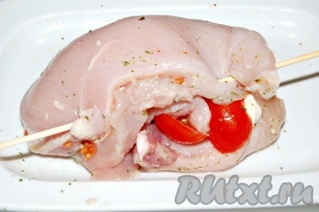Сложить куриное филе так, чтобы помидоры и моцарелла оказались внутри и скрепить края мяса с помощью зубочистки (или деревянной шпажки).
