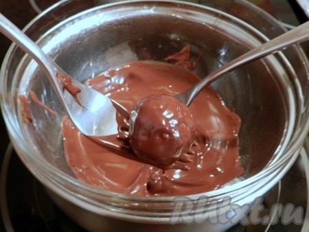 С помощью двух вилок окунать шарики в шоколад, обмазывать со всех сторон. сли хотите получить более толстый слой шоколада, немного остудите конфеты и окуните в шоколад еще раз.