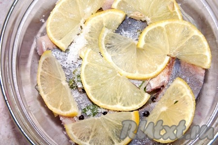 Выложить слоями, чередуя, нарезанные морковку и лук, солёную селёдку, специи, 0,5 чайной ложки сахара, кусочки лимона, верхний слой должен быть из лимонных ломтиков. Заранее сварить маринад, для этого влить в ковшик воду, добавить 1,5-2 чайных ложки сахара и сок лимона, довести до кипения, проварить 2 минуты, выключить огонь. Остудить маринад и он готов  к использованию. Залить холодный маринад в банку с селёдкой и убрать на 2 суток в холодильник.
