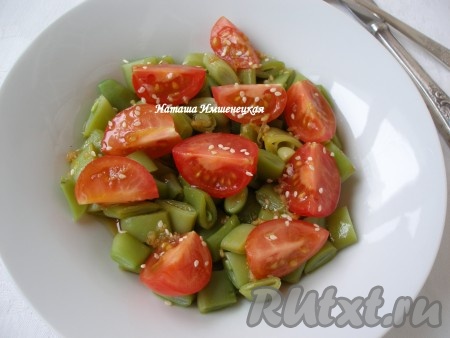 В тарелку выложить фасоль, дольки помидоров, полить салат заправкой и посыпать семенами кунжута.
