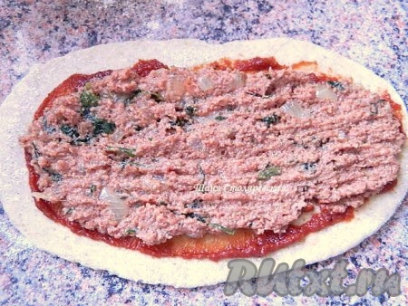 Для Лахмаджун раскатываем лепешку до 0,5 см толщиной. Смазываем ее томатным соусом и выкладываем начинку, но с каждого края оставляем чистое тесто.
