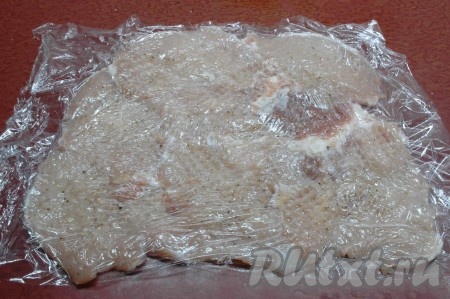 Выложить отбивные на пищевую плёнку, слегка внахлёст. Прикрыть сверху пищевой плёнкой и ещё раз отбить молоточком через плёнку, чтобы получился однородный мясной пласт. Затем верхнюю плёнку убрать.