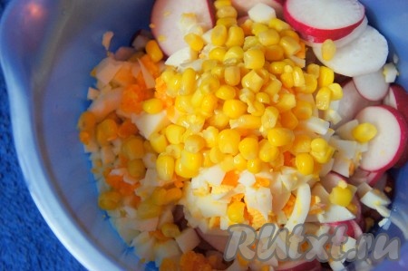 В салат из огурцов и редиски добавить кукурузу и нарезанные яйца (немного желтка оставьте для подачи салата).