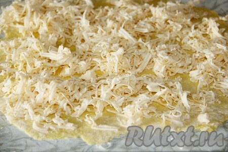 Для приготовления сырных рулетиков яйцо взбить с солью, добавить муку и замесить тесто. Из теста раскатать тонкий пласт, на который натереть плавленный сыр.
