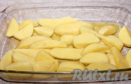 В форму для запекания налить растительное масло и выложить очищенный картофель, разрезанный на крупные дольки.