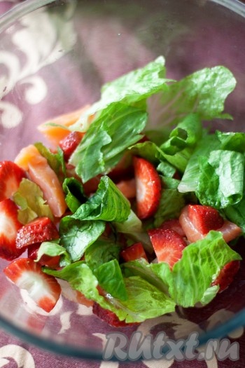 Нарежьте небольшими ломтиками копченого лосося и клубнику, положите в салатник и добавьте рваные листья салата (можно измельчить).
