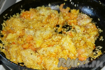 Перемешать рис с креветками и рыбой на сковороде.