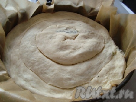 Сковороду смазать маслом или застелить антипригарной бумагой, выложить рулет спиралью. Сделать проколы вилкой, 2/3 соуса вылить на слоеный мясной пирог.
