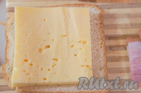 На два куска тостового хлеба выкладываем по кусочку сыра.