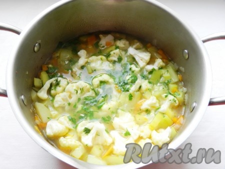 Когда картофель сварится, добавить в суп цветную капусту и мелко нарезанную зелень. Варить до готовности капусты, примерно 5 минут.
