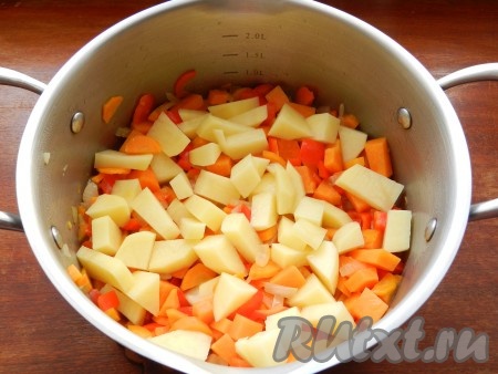 Затем в кастрюлю с обжаренными овощами добавить тыкву и картофель, перемешать, влить 700-80 миллилитров горячей воды, довести до кипения, посолить и поперчить по вкусу.