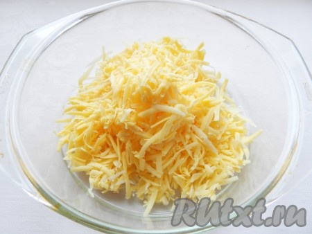 Сыр натереть на крупной тёрке, выложить в миску. Отложить, примерно, 2 столовые ложки натёртого сыра для посыпки пирога.