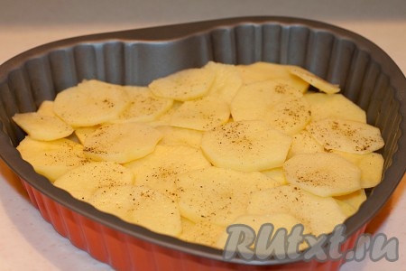 Картофель нарезать кружками средней толщины и уложить в форму для запекания, смазанную растительным маслом. Посыпать солью и черным перцем.