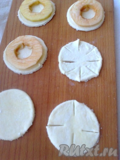 С помощью стакана из теста вырезать кружки. Половину кружков нарезать на лепестки. На один кружок  положить кружок яблока, накрыть вторым кружком.