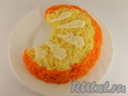 Внешний край "апельсиновой дольки" украсить натертой на крупной терке морковью. Сверху на сыр нанести майонез в виде капелек.