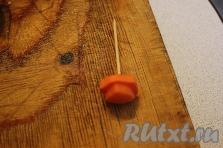 Вырезать из морковки два кружочка для шляпы снеговика: один побольше, второй поменьше и закрепить их зубочисткой
