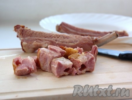Достать из кастрюли варёные рёбрышки, дать немного остыть. Отделить мясо от костей. Нарезать мясо на небольшие кусочки.