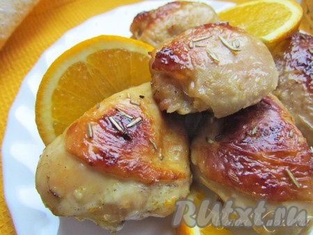 Готовую курицу переложите на блюдо, полейте выделившимся при запекании соком и украсьте дольками свежего апельсина.

