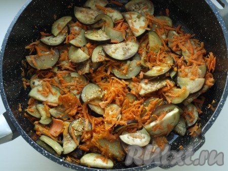 Очищаем морковь и зубчик чеснока. Из болгарского перца убираем плодоножку с семенами. Нарезаем баклажаны на достаточно тонкие полукружочки, солим, оставляем минут на 30, чтобы сошла горечь, затем промываем водой и обсушиваем, выложив на бумажное полотенце. Морковь натираем на крупной тёрке. В сковороде разогреваем растительное масло, выкладываем баклажаны с морковью, перемешиваем и обжариваем 2-3 минуты, затем накрываем крышкой, немного уменьшаем огонь и тушим минут 10, периодически помешивая.