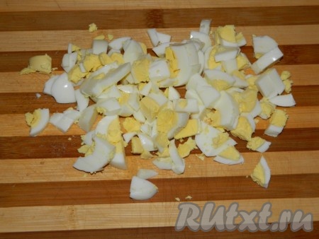 Яйца заранее отвариваем вкрутую (в течение минут 9-10 после закипания воды), затем даём им остыть и очищаем. Нарезаем яйца на небольшие кусочки, перекладываем в объёмную миску.