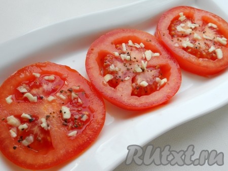 Выложить кружки помидоров на блюдо, посолить, посыпать смесью перцев и измельченным чесноком.