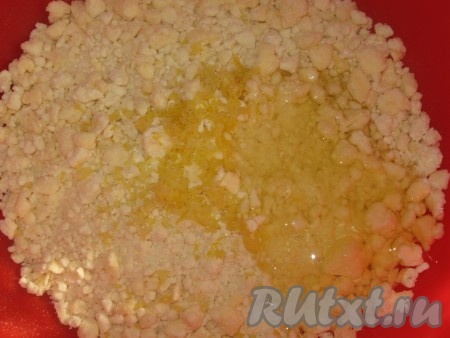 Затем крошку пересыпать в широкую миску, добавить цедру и белок яйца, замесить мягкое, пластичное тесто, скатать его в шар, завернуть в пищевую пленку и убрать в холодильник на 30 минут.