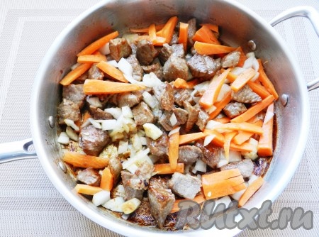 Лук нарезать кубиками, морковь нарезать брусочками, чеснок измельчить. Лук и морковь добавить в сковороду к мясу, обжарить все вместе, затем добавить чеснок и обжарить еще 1 минуту.