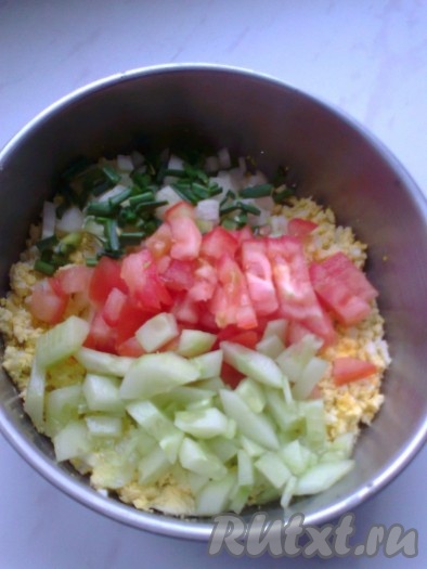 Половину помидора,  оставшийся огурец и зеленый лук нарезать кубиками и добавить к желткам и белкам.
