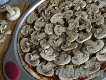 Шампиньоны режем пластинами и плотно выкладываем на пиццу, посыпаем орегано и базиликом. 
