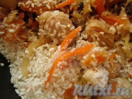 Добавьте к смеси мяса, овощей и сухофруктов сухой рис, посолите, хорошо перемешайте и обжаривайте, помешивая, ещё минут 5, пока рис не станет слегка прозрачным.