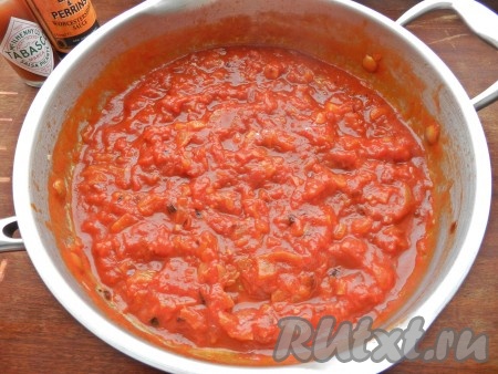 К луку добавить нарезанный чеснок и выложить томаты в собственном соку. Довести до кипения и проварить соус в течение 5 минут.
