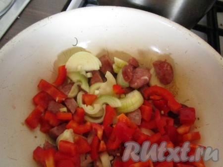 Сладкий перец и репчатый лук крупно нарежьте и добавьте в сковороду к обжаренным кусочкам колбасы. Тушите овощи с колбасой, помешивая, минут 5-10.
